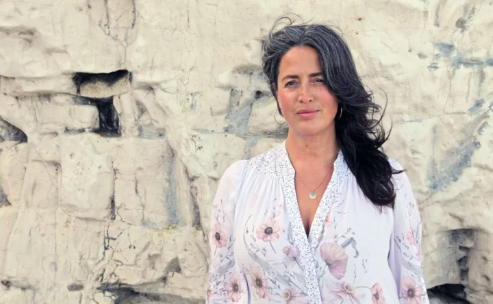 Sarah standing in front of a chalk cliff wearing a white floral dress.